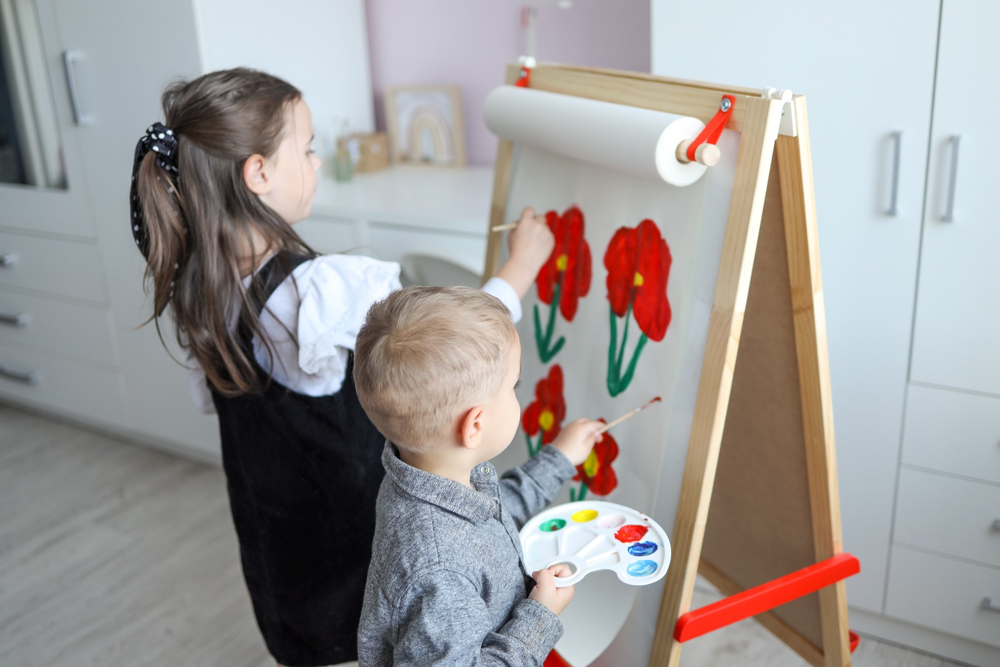 Children paint flowers on an easel, drawing lesson